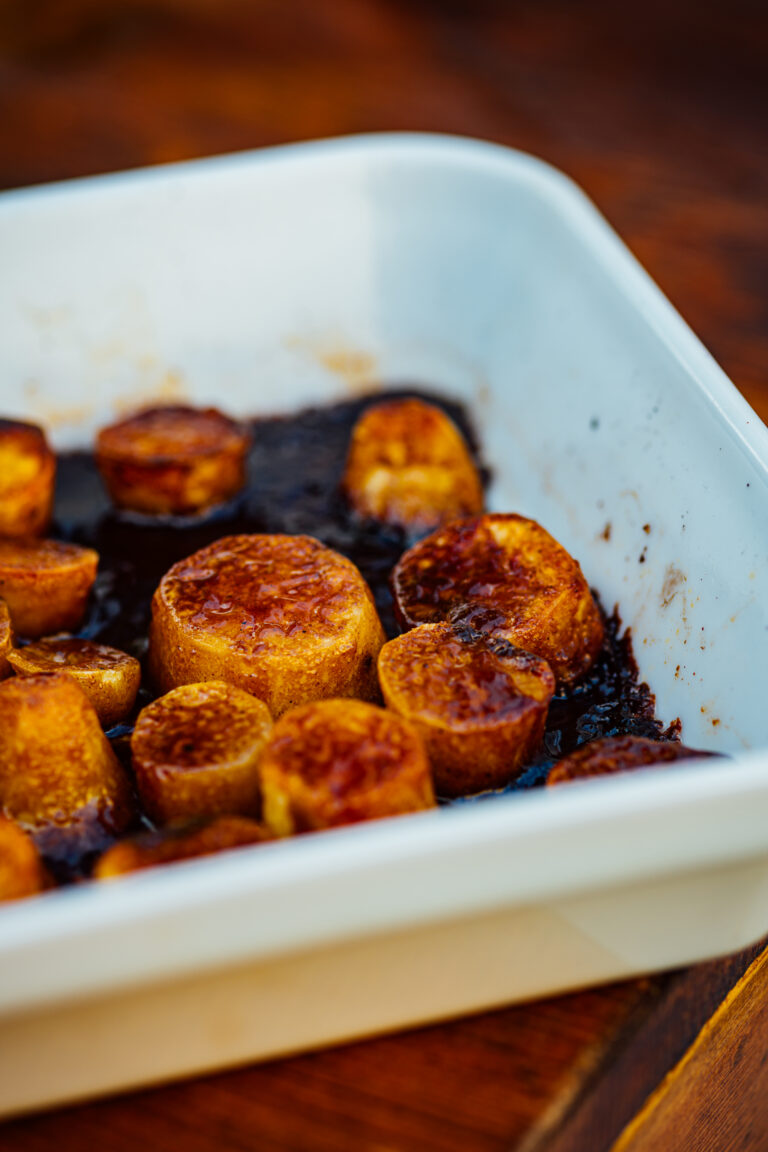 Chai-spiced candied sweet potatoes glazed with jaggery and topped with warm holiday spices.