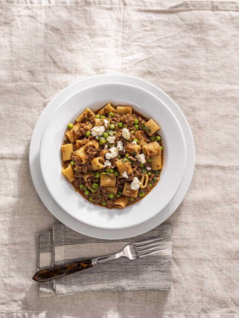 Goan keema pasta with ground beef, garam masala, Kashmiri chile, peas, and crumbled feta served in a bowl